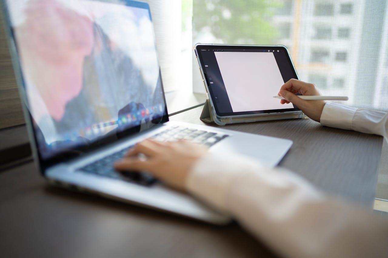 Modern workspace with laptop and tablet in use, ideal for remote work and digital creativity.