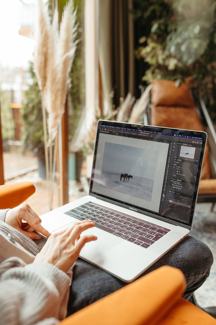 Crafting Captivating Headlines: Your awesome post title goes here A person using a laptop for photo editing indoors with natural light.